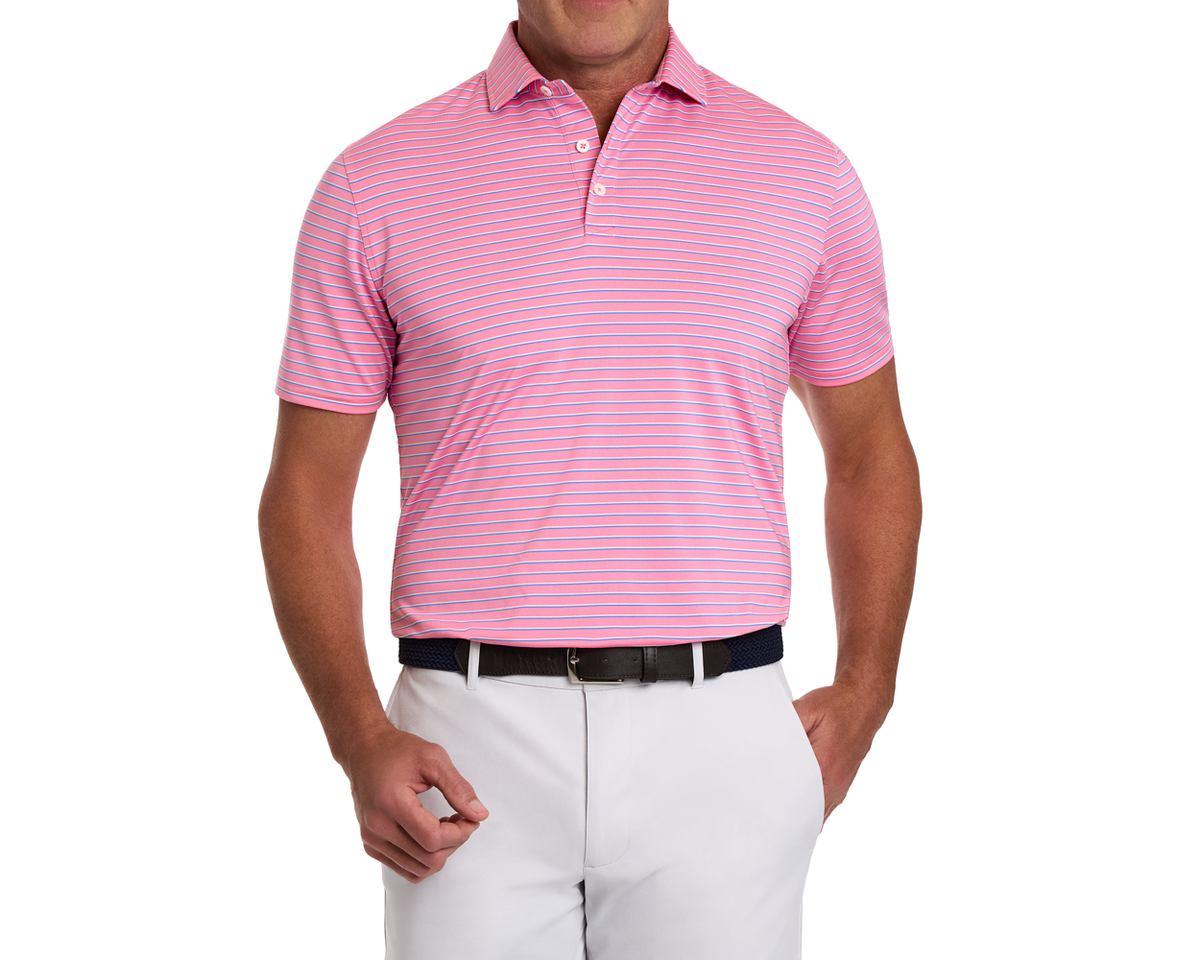 Man wearing The Springer Shirt: pink with white stripes, two-button placket, tucked into light trousers with a dark belt, showcasing performance knit features.