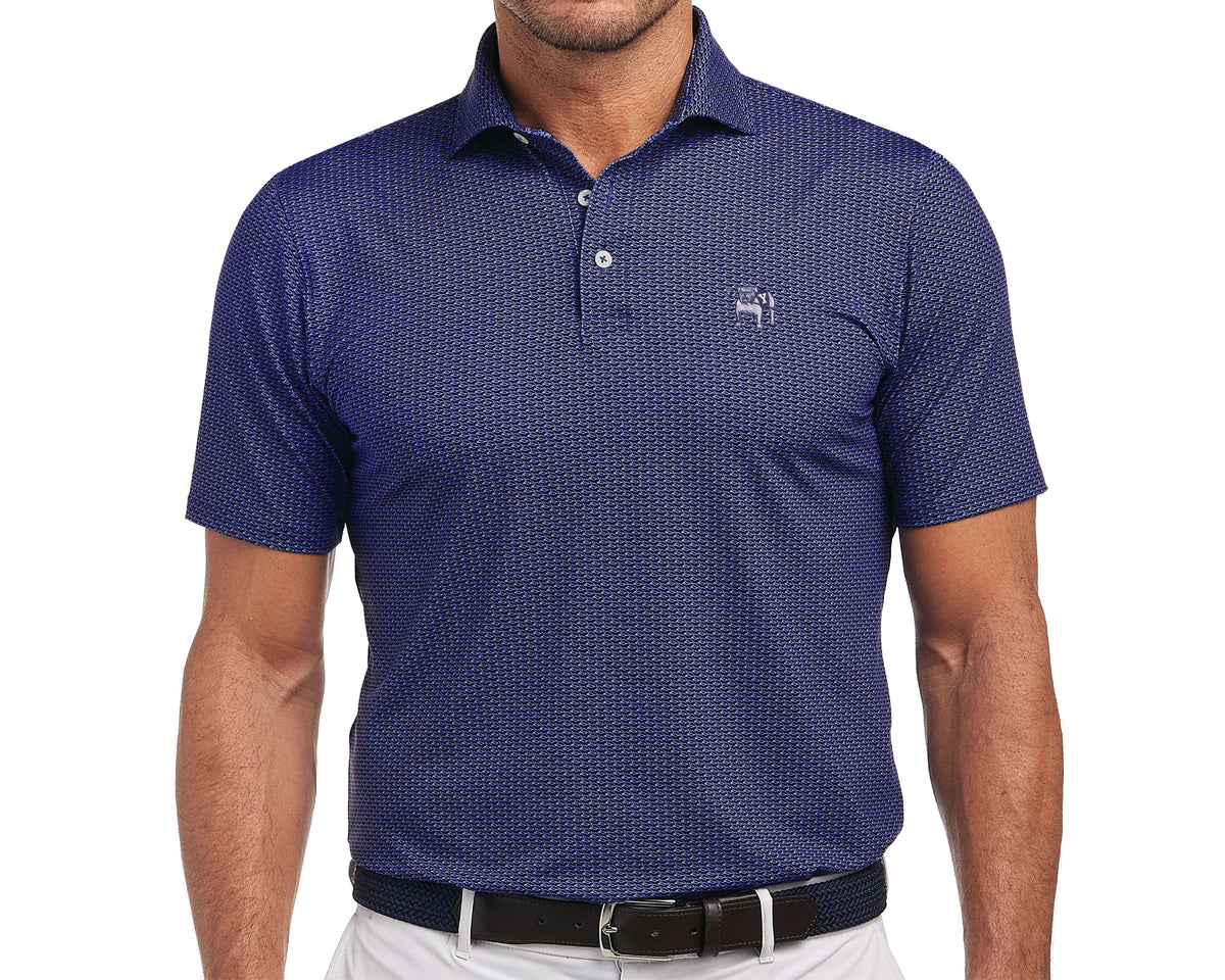 Man wearing Yale Golf Course Frame Shirt: Navy & White, featuring a small visor pattern and bulldog logo, tucked into light trousers with a woven belt.