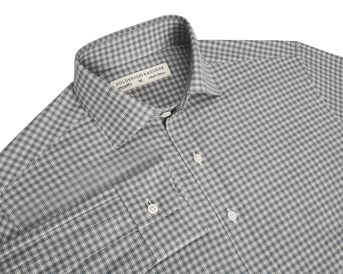 Close-up of a green checkered longsleeve shirt with a brand label on a white background