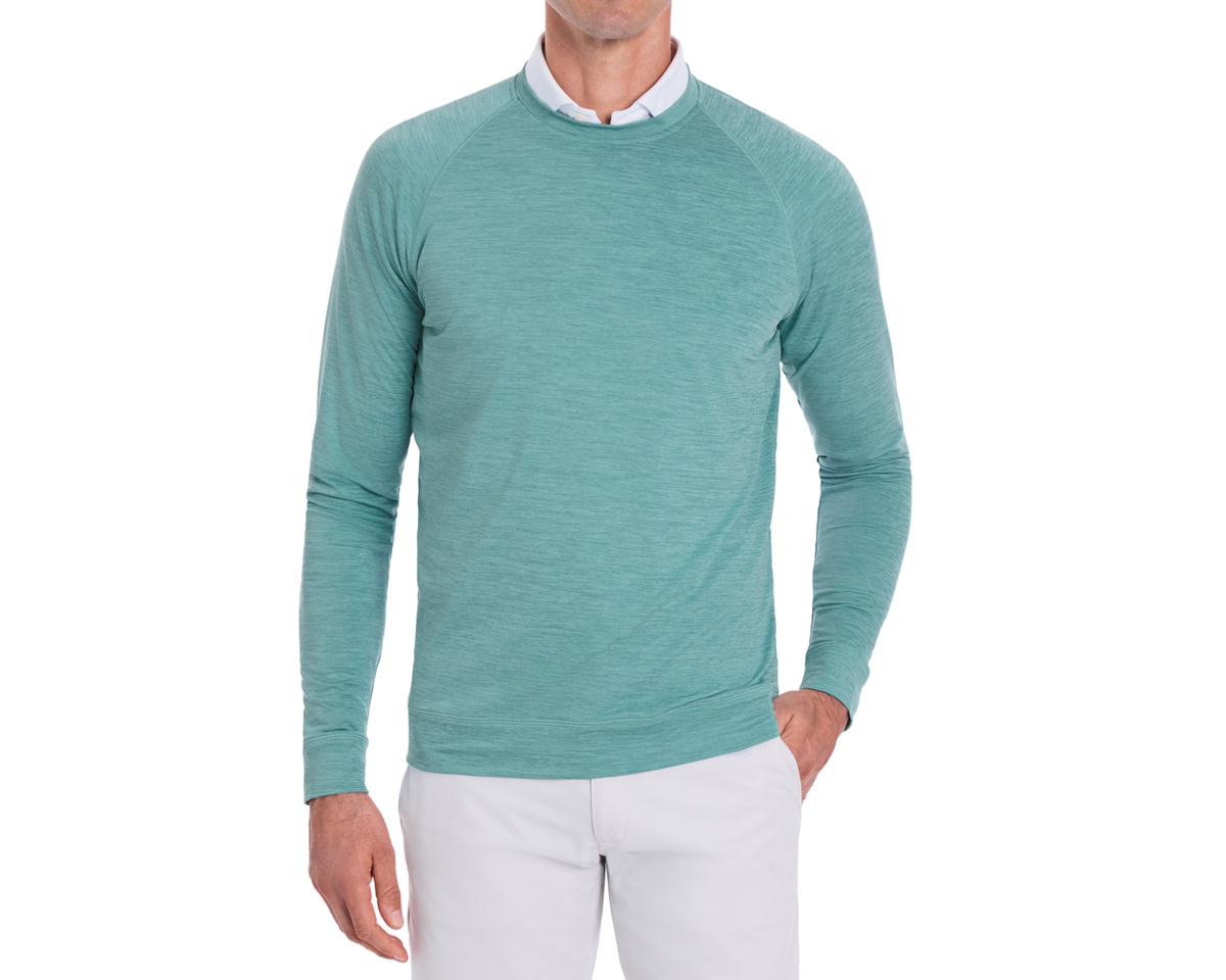 Person wearing The Laidlay Crewneck: Heathered Harbor over a white collared shirt, paired with light trousers, showcasing its soft, stretchy fit and heathered texture.