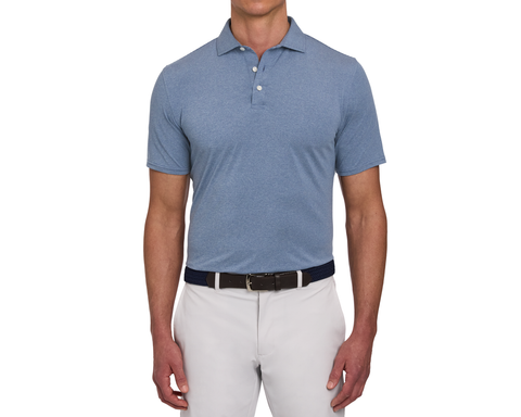 Model wearing The Holland Shirt: Heathered Pacific Blue, featuring a heathered finish and short sleeves, paired with a woven belt and light gray pants.