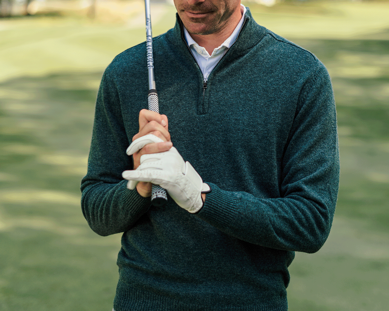 Man in Holderness & Bourne Men’s Olive Green Quarter Zip Sweater holding a golf club on a golf course