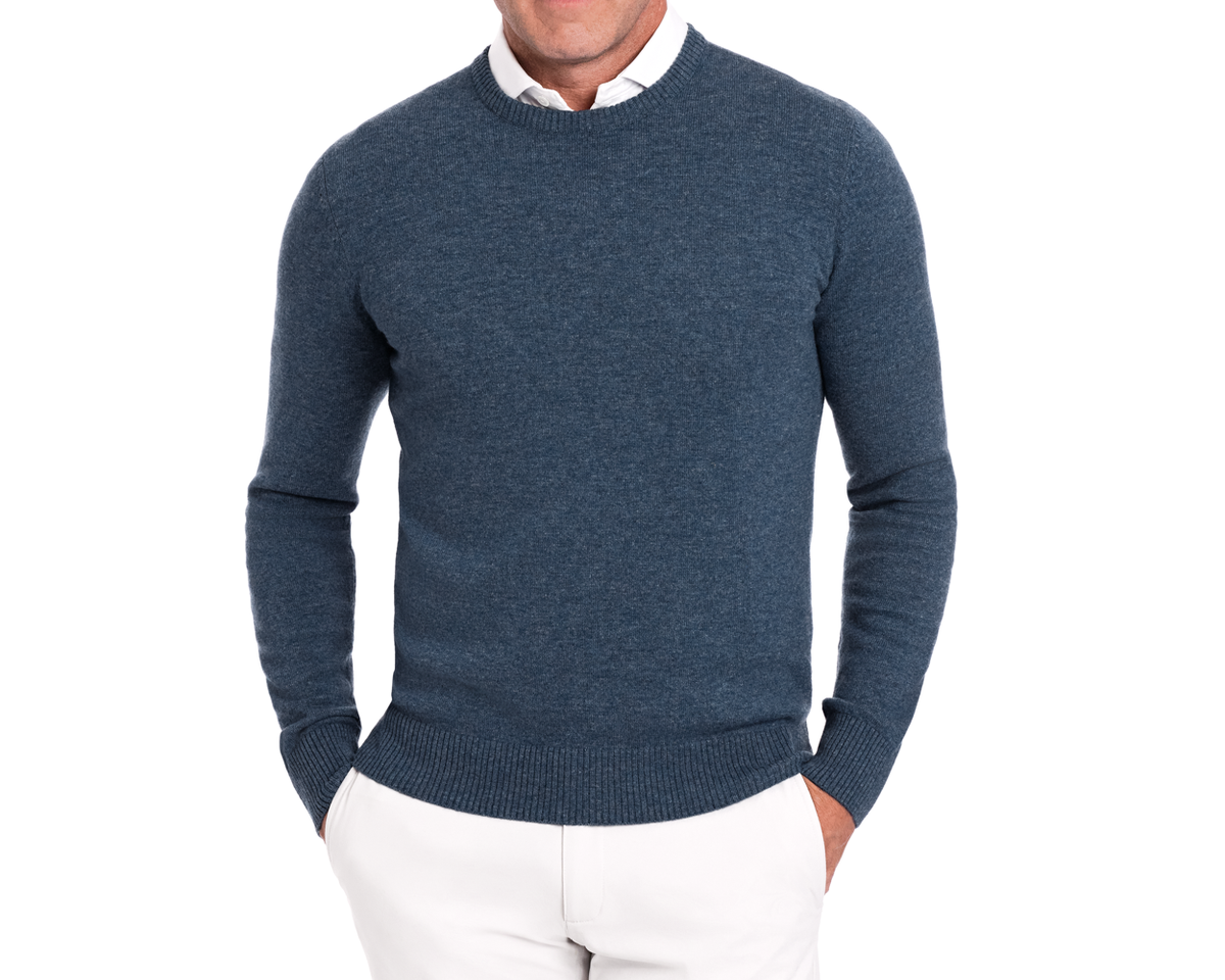 Man wearing Holderness & Bourne Men’s Blue Knit Sweater over a white shirt on a white background