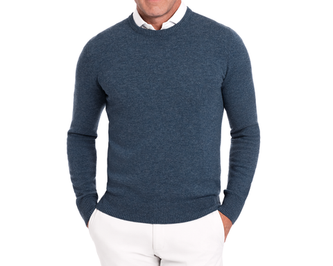 Man wearing Holderness & Bourne Men’s Blue Knit Sweater over a white shirt on a white background