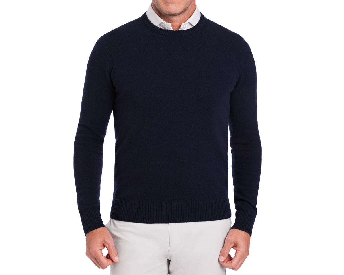 Man wearing Holderness & Bourne Men’s Navy Crewneck Sweater over a white shirt on a white background