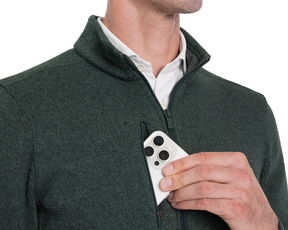 Person wearing a Holderness & Bourne Men’s Dark Green Fleece Jacket holding a smartphone with a white case.