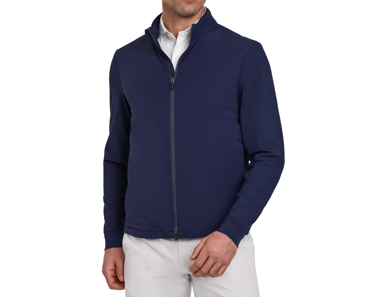 Man wearing a navy blue golf jacket over a white shirt on a white background