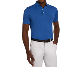Man wearing The Anderson Shirt: Maidstone Blue, a short-sleeve polo with structured collar, tucked into shorts, accessorized with a dark woven belt.