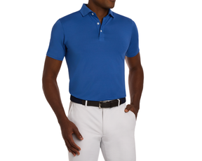 Person wears The Anderson Shirt: Maidstone Blue, a polo with short sleeves, tucked into trousers, cinched by a dark belt, showcasing elegance and comfort.