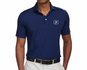 Man wearing the 2026 U.S. Open Anderson Shirt: Navy, featuring a three-button placket, logo embroidery, and a structured collar, paired with light trousers and a woven belt.