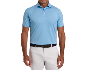 Man wearing The Anderson Shirt: Vista Blue, a light blue polo with a structured collar, tucked into off-white trousers with a dark braided belt.