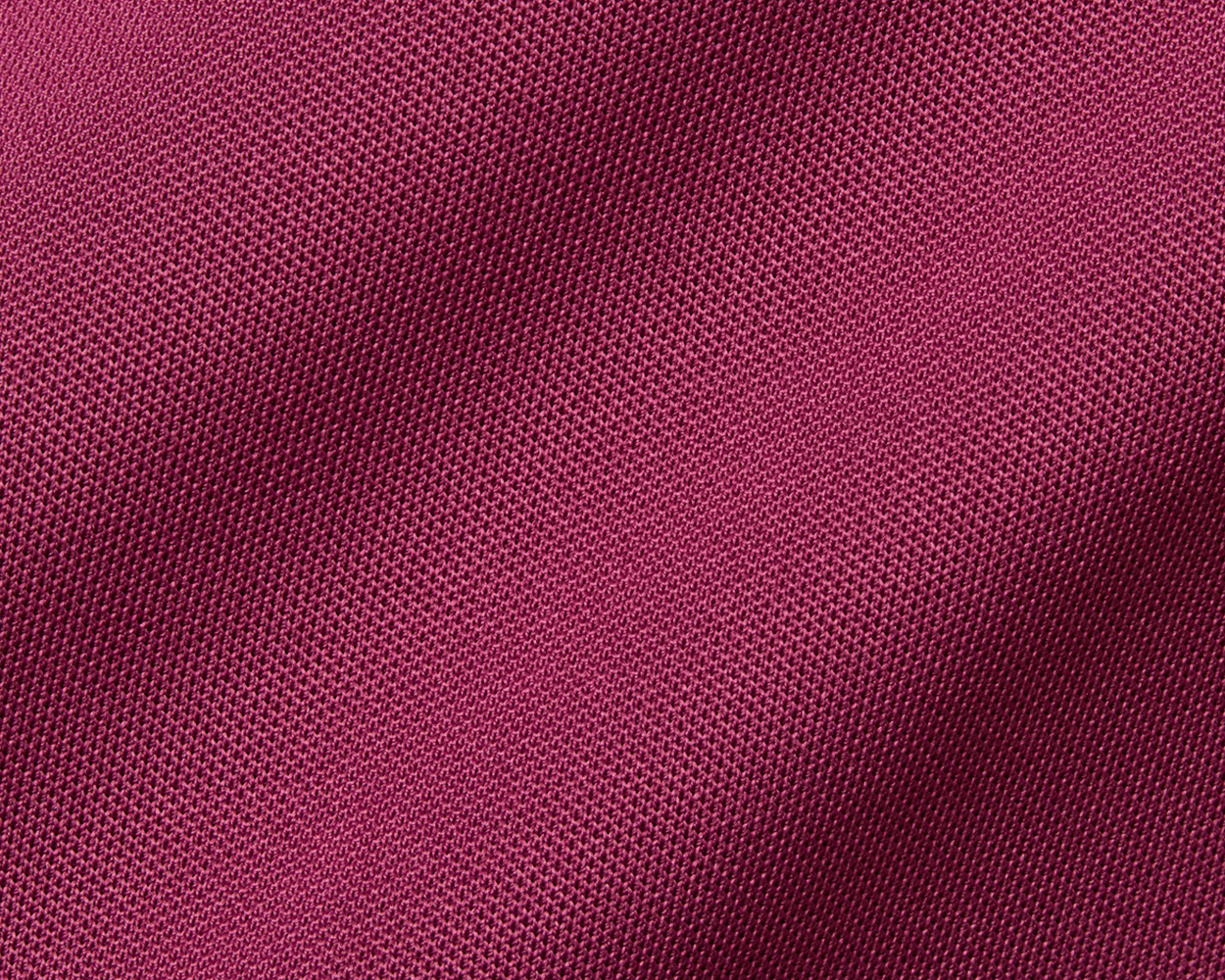 Close-up of magenta knit fabric detailing the 2026 U.S. Open Macdonald Shirt: Cabernet, showcasing its breathable mesh texture and honeycomb pattern.
