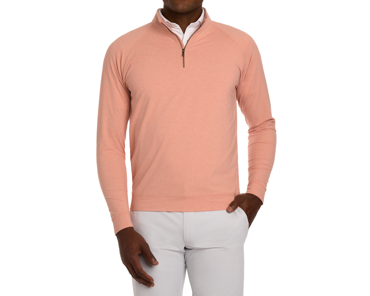Model wearing The Westland Quarter-Zip: Heathered Nectarine over a white shirt with light gray trousers, showcasing its soft, moisture-wicking fabric and versatile style.