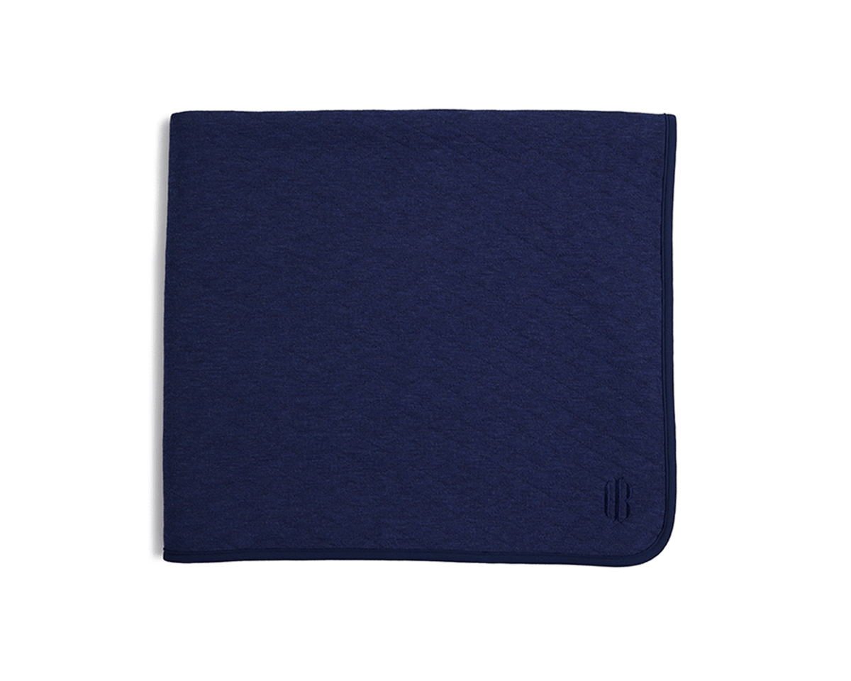 The Van Pelt Blanket: Heathered Navy; a folded, navy blanket with a piped border and tonal embroidered logo, ideal for cozy evenings.