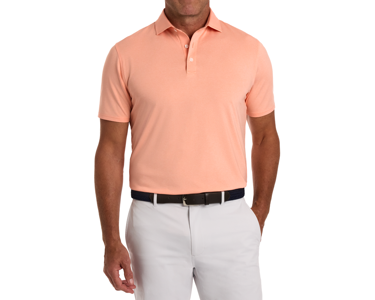 Man wearing The Holland Shirt: Heathered Nectarine, a short-sleeve polo with subtle stripes, tucked into light trousers, featuring a structured collar and dark woven belt.