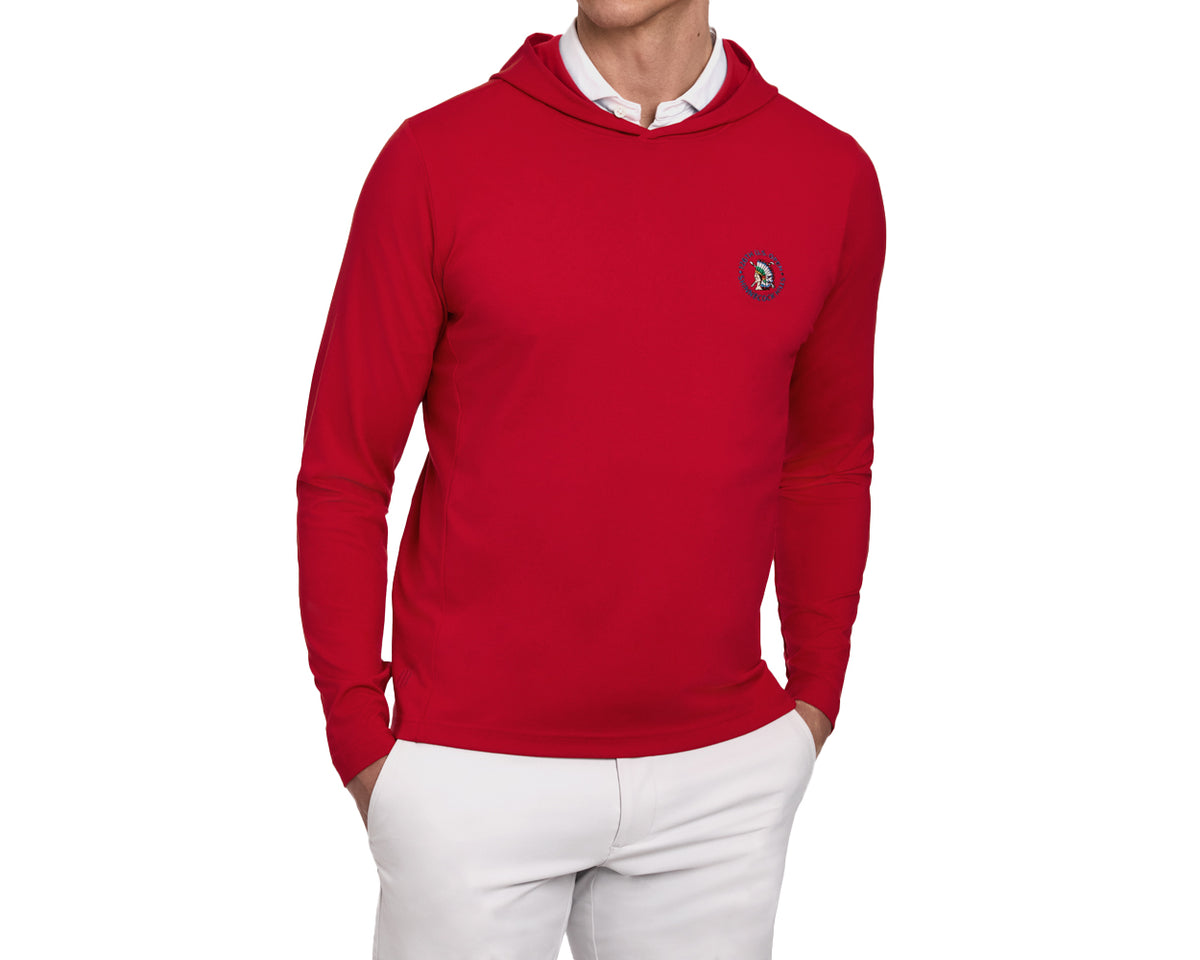 Model wearing 2026 U.S. Open Jackson Pullover: Liberty, a red hooded sweatshirt with an emblem, over a white collared shirt, paired with white trousers.