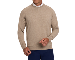 Model wearing The Kennedy Crewneck: Heathered Dune, showcasing a light tan sweatshirt over a white collared shirt with dark blue trousers.