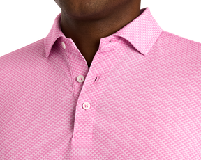 Wearing The Eaton Shirt: Belmont, showcasing a short-sleeve pink polo with a white wave pattern, pointed collar, and three-button placket.