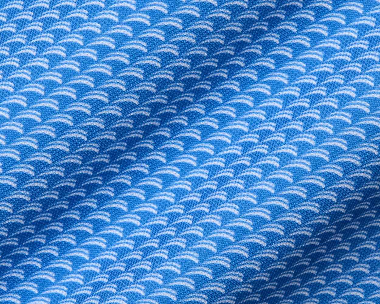The Eaton Shirt: Horizon Blue, showcasing a close-up of its soft, stretchy fabric with a white, semi-circular wave pattern, designed for moisture wicking and sun protection.