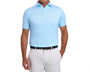 Man wearing The Eaton Shirt: Vista Blue, featuring a short-sleeve polo style with abstract wave pattern, tucked into light trousers with a dark belt.