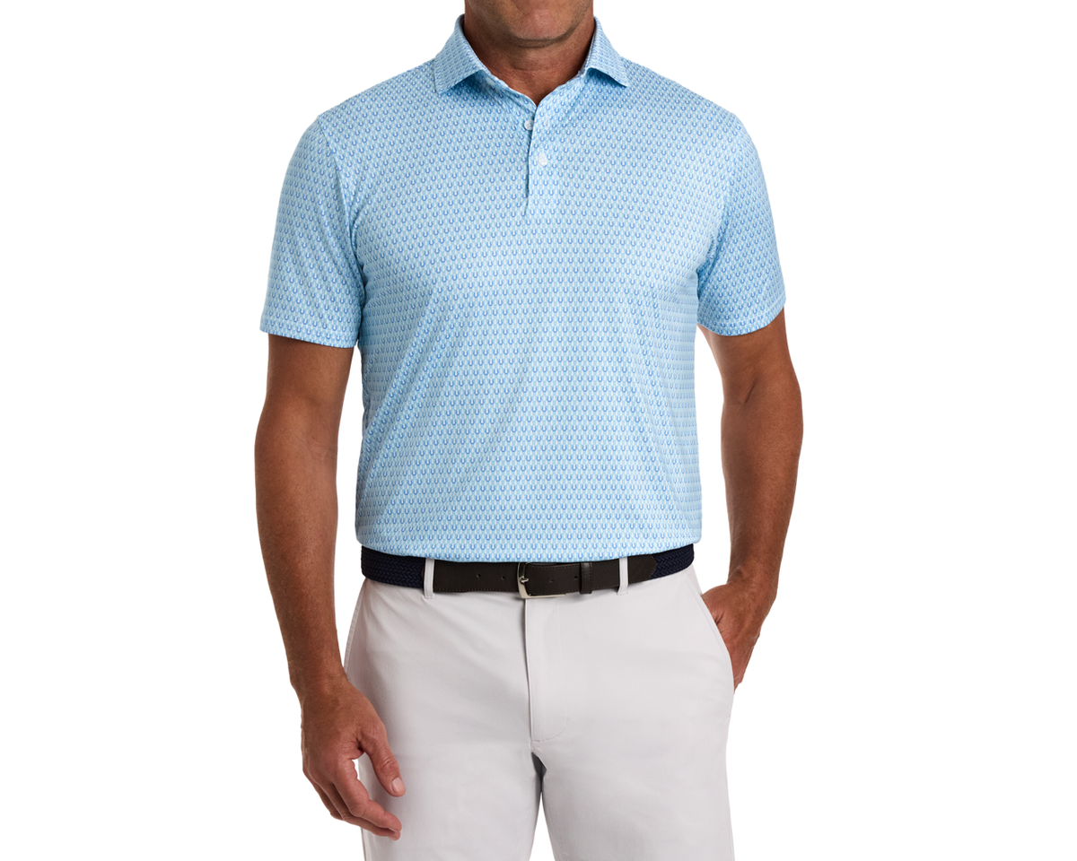 Man wearing The Rivers Shirt: Harbor & Maidstone Blue polo with a subtle horseshoe pattern, paired with light trousers and a dark woven belt.