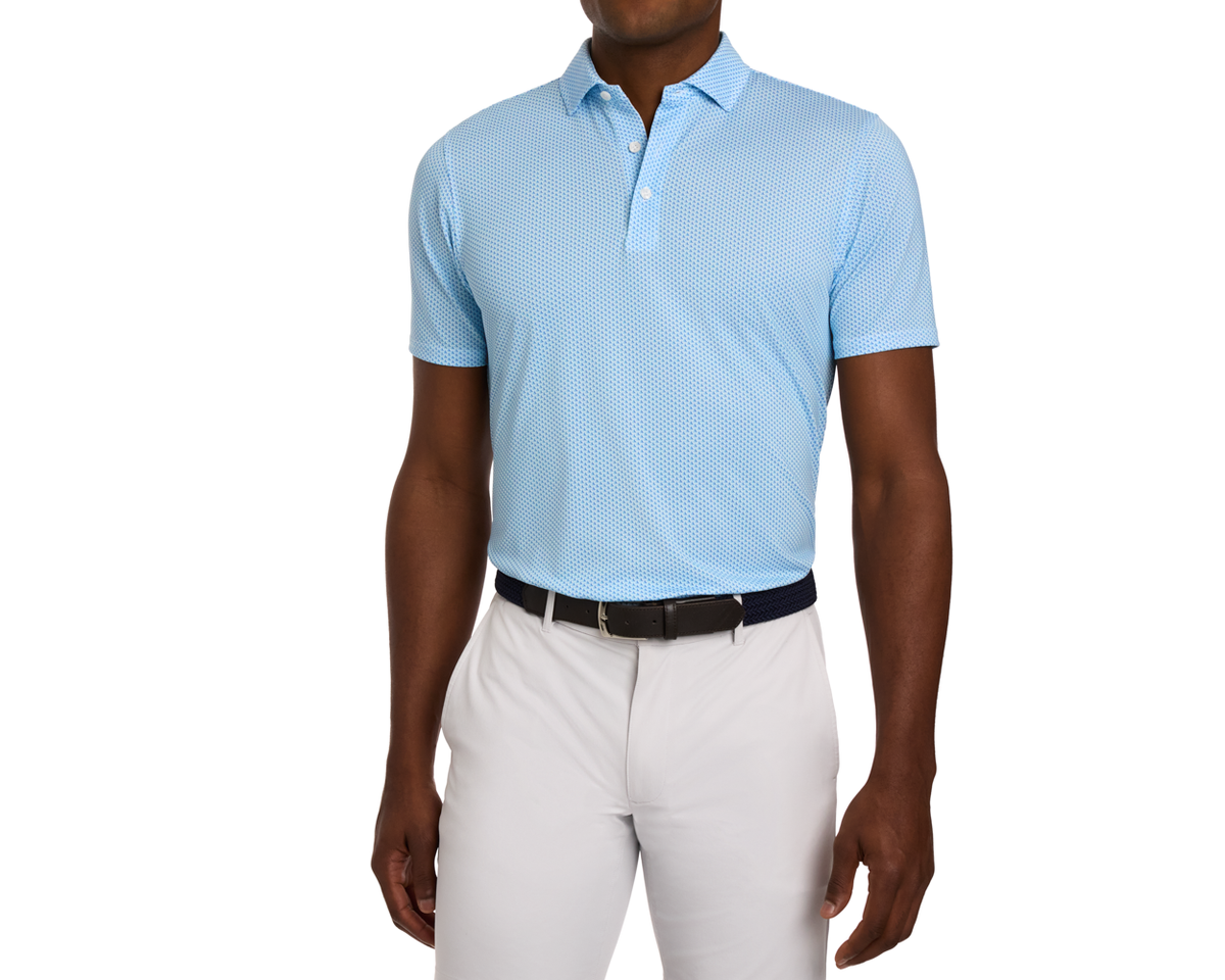 The Lennox Shirt: Harbor & Maidstone Blue, featuring a subtle dot pattern, short sleeves, and a structured spread collar, paired with light gray trousers and a black belt.