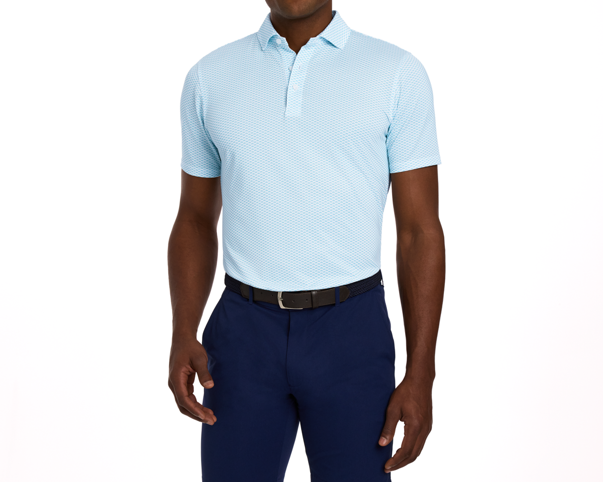 Man wearing The Geiger Shirt: Harbor, a light-blue patterned polo with navy trousers and a black belt, showcasing its breathable, moisture-wicking performance pique.