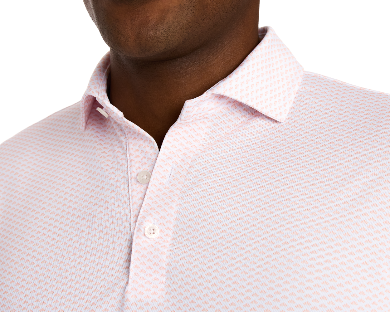 The Geiger Shirt: Nectarine features a light pink collared design with a small dot pattern, showcasing white buttons and breathable, moisture-wicking pique fabric.