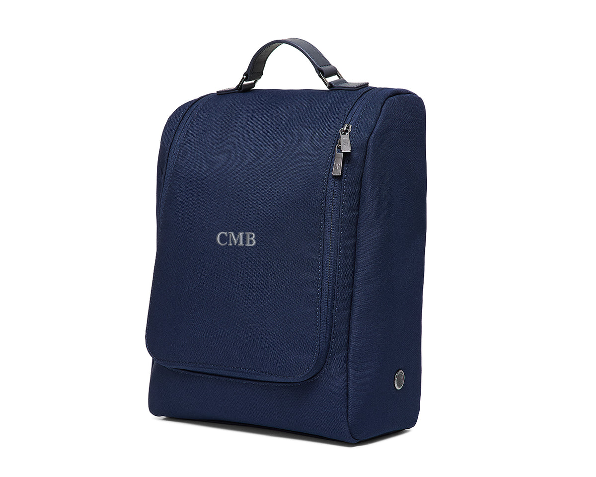 The Rutledge Shoe Bag: Navy Ballistic - Slate Blue Embroidery, features a top handle, zippered side, fold-over flap with “CMB” initials, and a circular metal port.