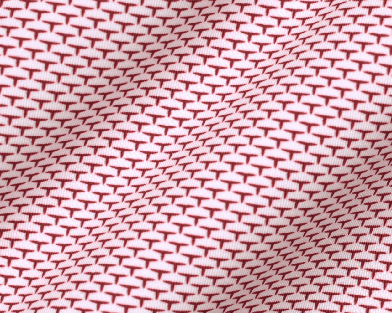 The Armfield Shirt: Liberty Red features a close-up of its red “T”-shaped motif on light fabric, highlighting the refined geometric pattern and texture.