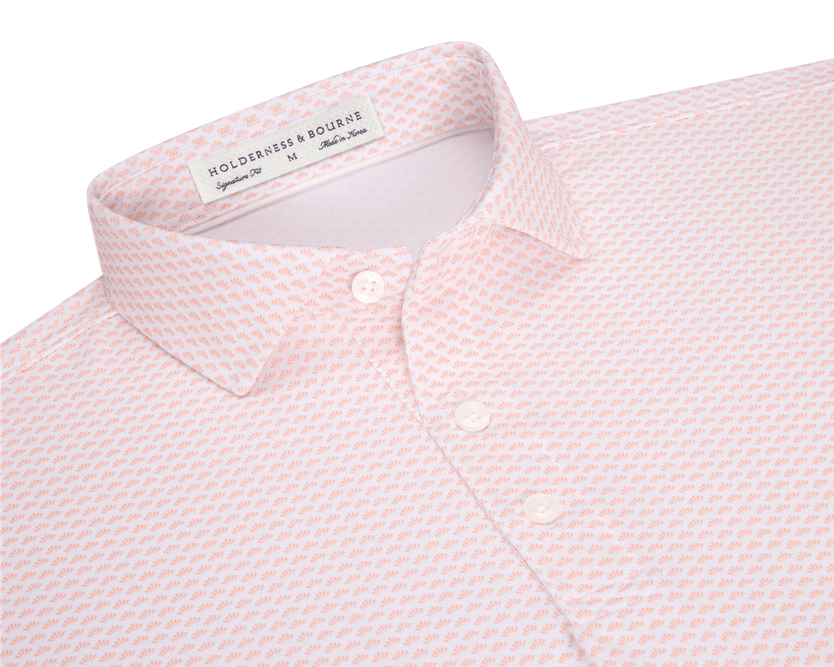 The Geiger Shirt: Nectarine, featuring a tiny orange fan motif, collared with three visible buttons, offers breathable, moisture-wicking performance pique and UPF 30+ protection.