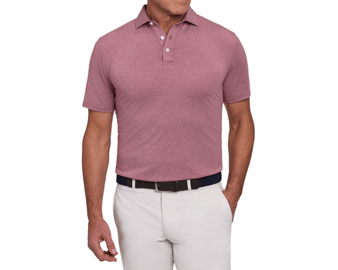 Model wearing The Holland Shirt: Heathered Napa, featuring a heathered finish and short sleeves, paired with a woven belt and light gray pants.