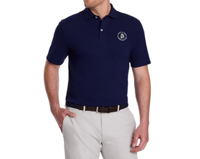 Man wearing the 2026 U.S. Open Neville Shirt: Navy, featuring embroidered logo, tucked into light gray trousers, styled with a dark belt.