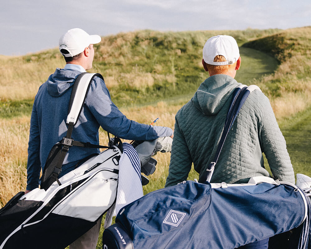 two golf players holding golf bags