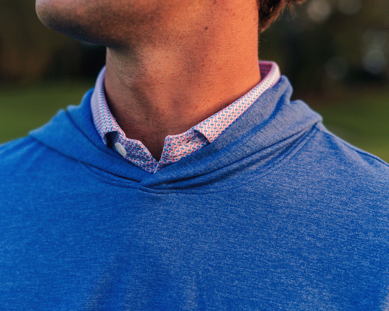 The Stowe Hoodie: Heathered Maidstone Blue, shown layered over a patterned shirt, features a lightweight, ultra-soft fabric with set-in sleeves and a drop-tail hem.