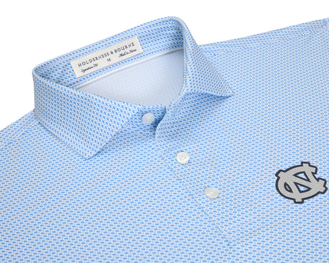 Close-up of University of North Carolina Norman Shirt: Vista Blue & Horizon Blue showing its spread collar, white buttons, geometric basketweave print, and NC logo on the left chest.