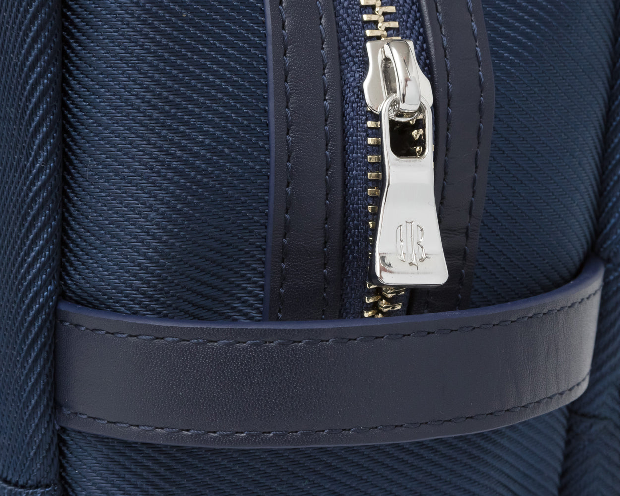 Close up on silver zipper and leather detailing on navy Holderness and Bourne dopp kit.
