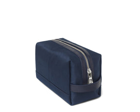 Navy dopp kit with silver zipper from Holderness and Bourne angled to the side.