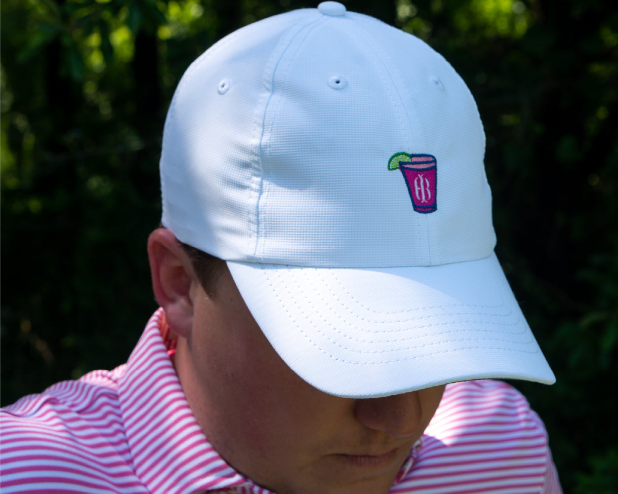 Man wearing Holderness and Bourne white icon hat and pink striped polo. 
