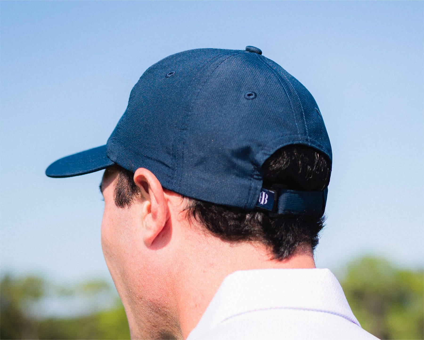 Back of mans head wearing Holderness and Bourne navy white hat.