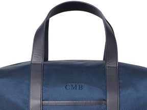 Navy embroidered duffle bag with dark leather straps and embroidered lettering from Holderness and Bourne.